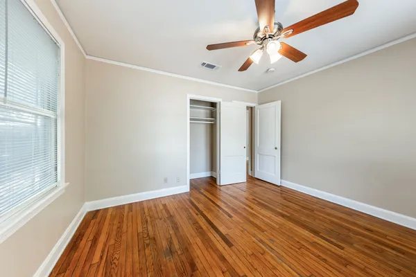 a view of an empty room with wooden floor and a window