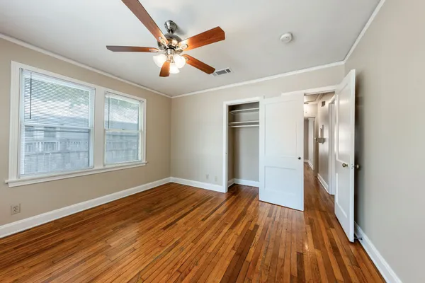 a view of an empty room with wooden floor and a window