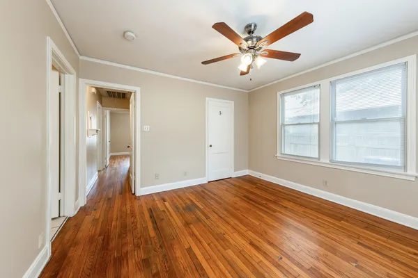 a view of empty room with wooden floor and fan
