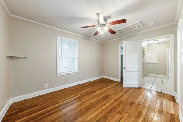 a view of an empty room with wooden floor and a window