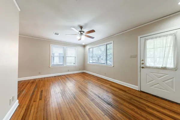 an empty room with wooden floor and windows