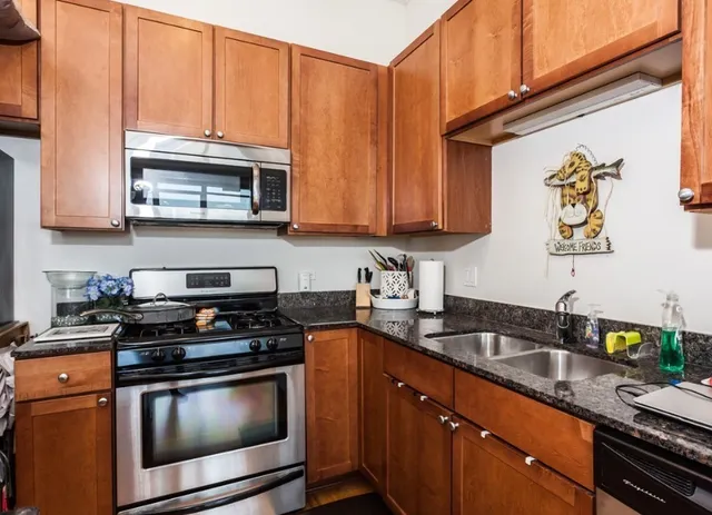 a kitchen with stainless steel appliances granite countertop a stove a sink and a microwave