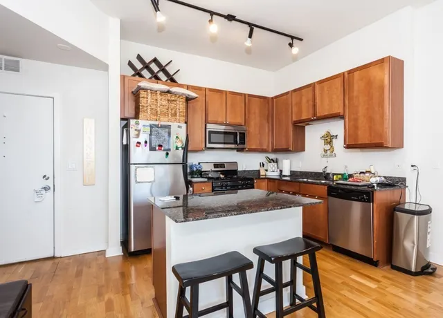 a kitchen with stainless steel appliances granite countertop a refrigerator a stove top oven a sink and dishwasher