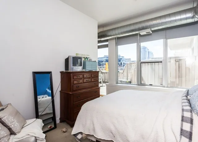 a bedroom with a bed windows and a television