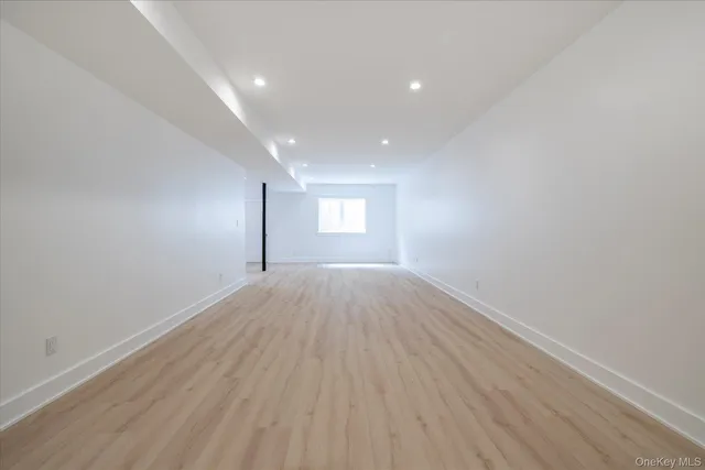 a view of empty room with window and wooden floor