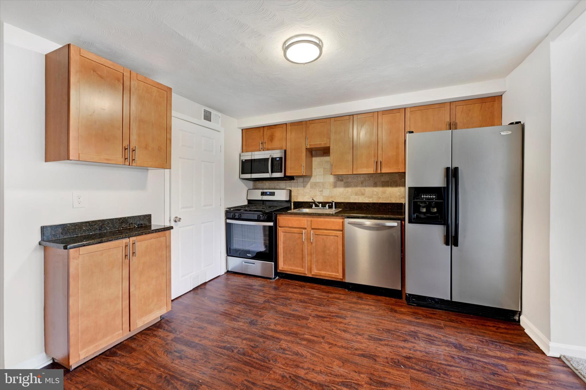 4436 Annapolis Road Halethorpe, MD 21227 - Photo 11 of 30 a kitchen with granite countertop wooden floors stainless steel appliances and sink