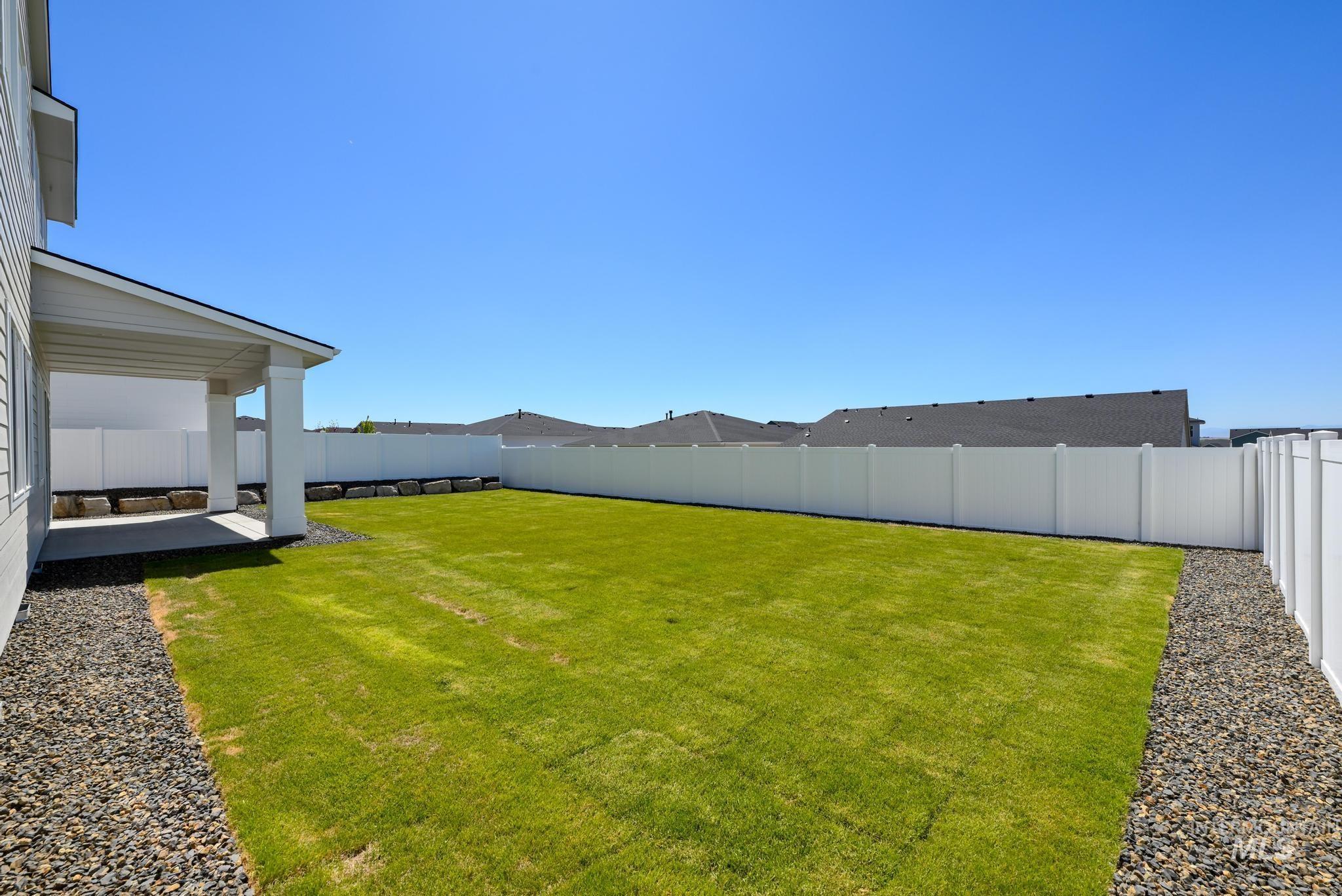 14703 Serenity Pt Street Caldwell, ID 83607 - Photo 35 of 45 Expansive backyard featuring a covered concrete patio, lush green lawn, and full privacy fencing