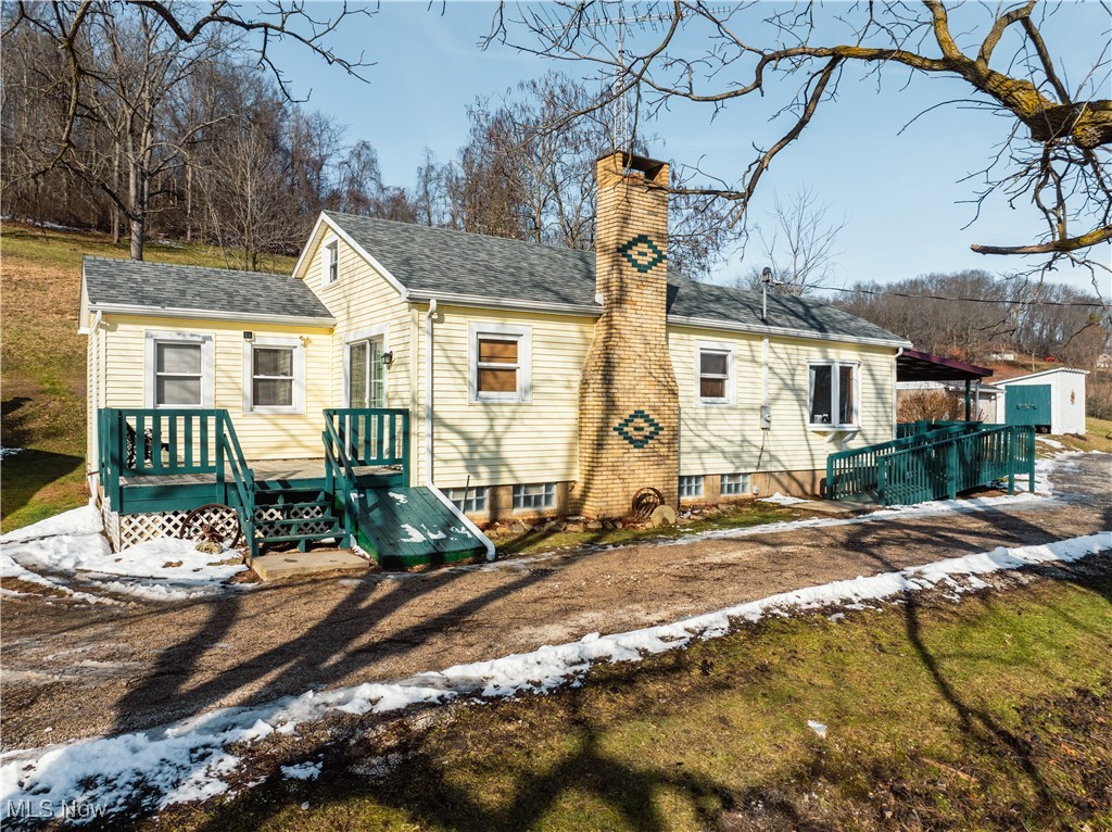 Back of property with a chimney, roof with shingles, and an outdoor structure