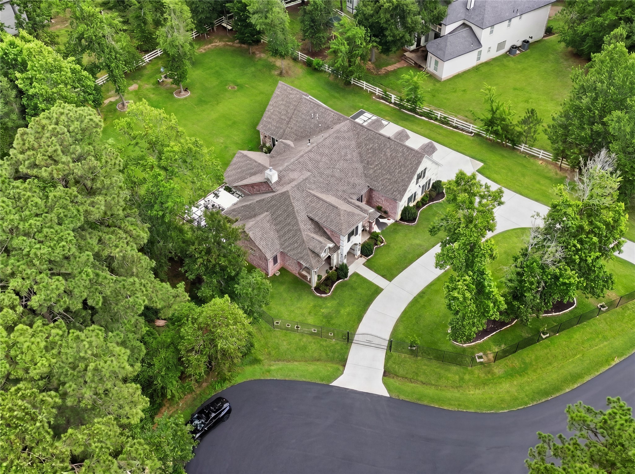 7106 Hampton Court Spring, TX 77389 - Photo 23 of 31 Aerial view showcases a fully gated spacious, elegant home with a well-maintained lawn and a large, curved driveway. The property is surrounded by lush greenery and trees, offering privacy and a serene atmosphere in a desirable neighborhood.