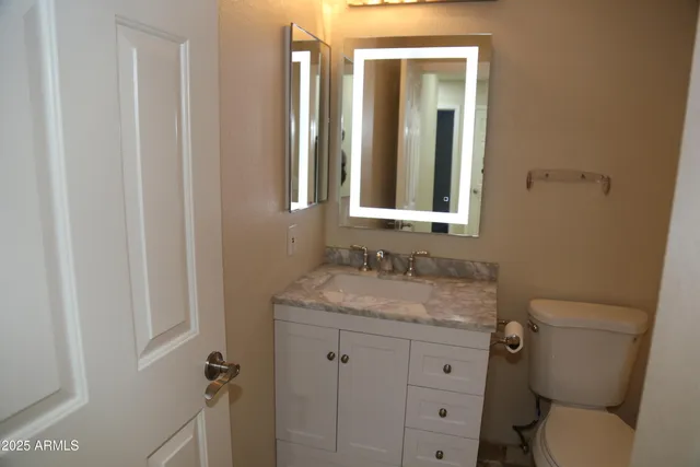 a bathroom with a granite countertop toilet sink and mirror