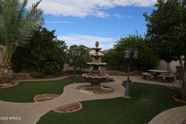 a view of a swimming pool and lounge chairs in back of the green field