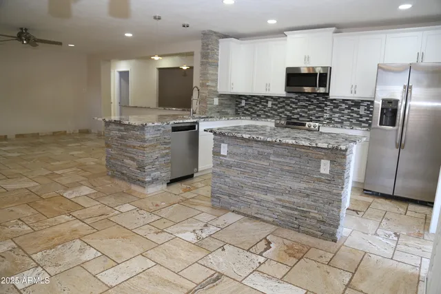 a kitchen with kitchen island granite countertop a sink cabinets and stainless steel appliances