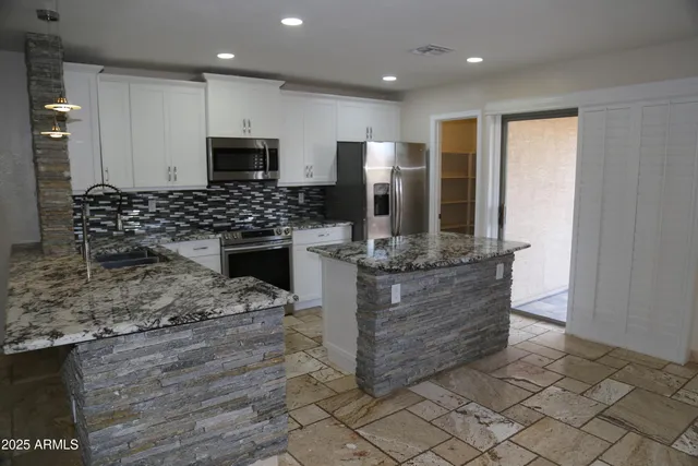 a kitchen with stainless steel appliances kitchen island granite countertop a stove and a refrigerator
