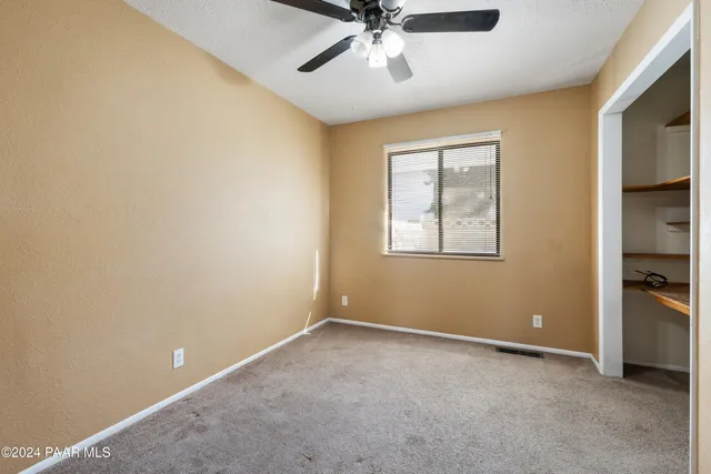 an empty room with windows and ceiling fan