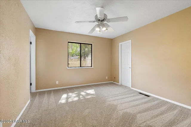 a view of a big room with windows and chandelier fan
