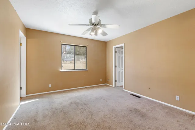 an empty room with windows and ceiling fan