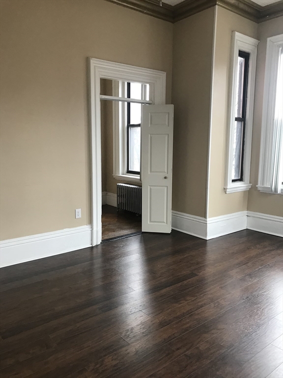 14 Monument Square, Unit 26 Boston, MA 02129 - Photo 5 of 7 an empty room with wooden floor and windows