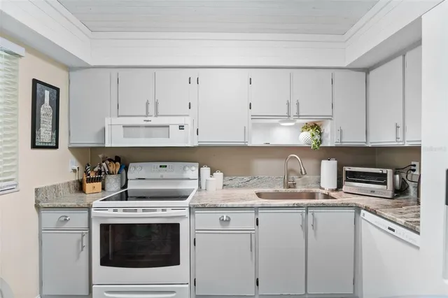 a kitchen with granite countertop white cabinets and white appliances