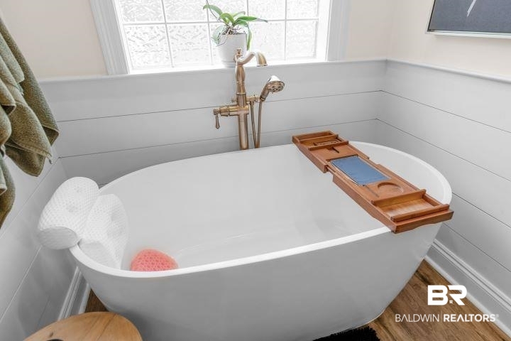 24541 Baldwin Beach Expressway Robertsdale, AL 36567 - Photo 29 of 51 Details featuring wainscoting, a freestanding tub, wood walls, and wood finished floors