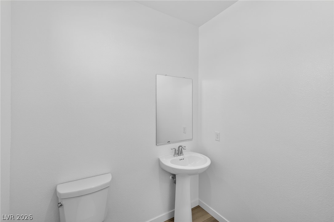 347 Sam Way Mesquite, NV 89027 - Photo 23 of 32 A minimalist powder room features a classic pedestal sink and toilet, offering clean lines and functional design.