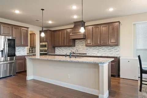 a kitchen with stainless steel appliances granite countertop a sink a stove and a refrigerator