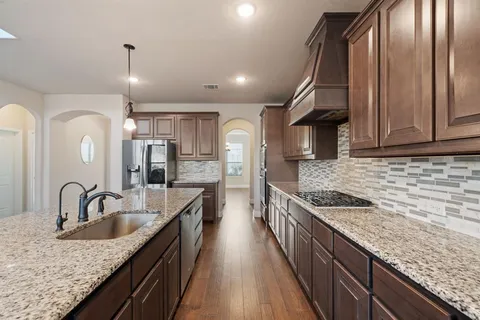 a kitchen with stainless steel appliances granite countertop a sink a stove and a wooden floors