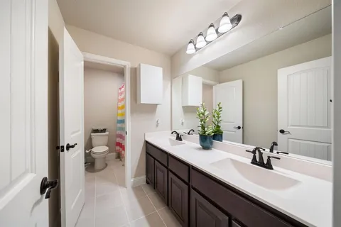 a en suite bathroom with a double vanity sink mirror and toilet