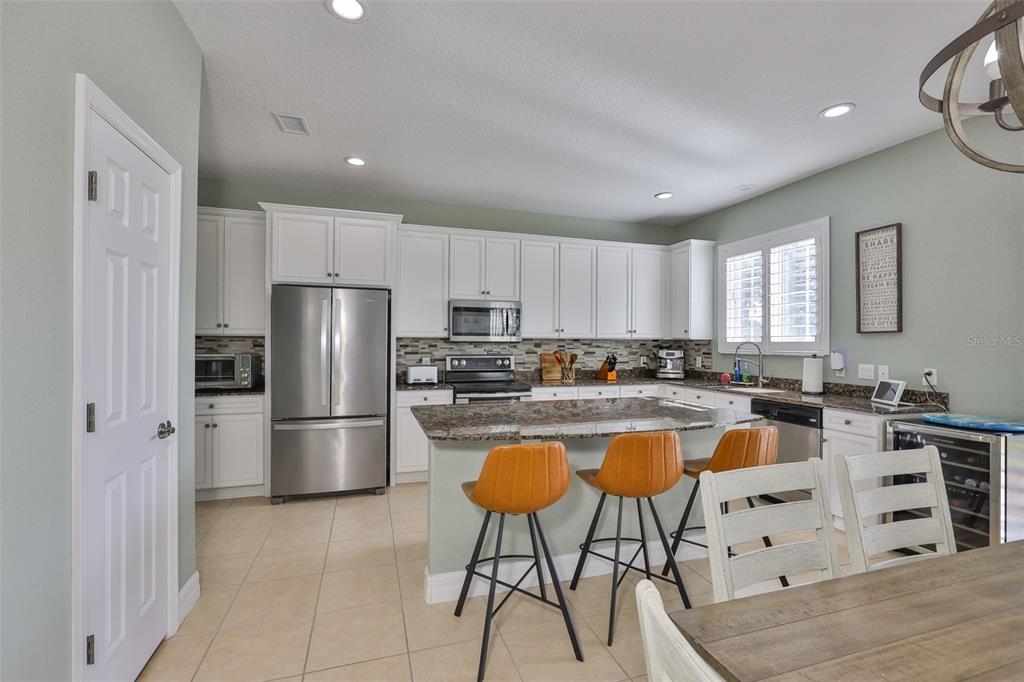 5409 Hammock View Lane Apollo Beach, FL 33572 - Photo 7 of 68 a kitchen with stainless steel appliances a refrigerator a stove a sink a dining table and chairs with wooden floor