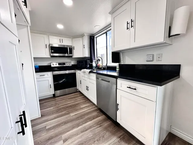 a kitchen with stainless steel appliances white cabinets a sink a stove a refrigerator and cabinets