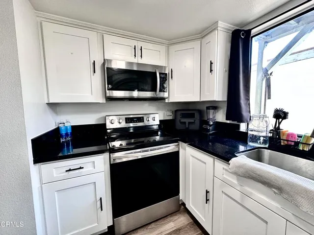 a kitchen with white cabinets and black appliances