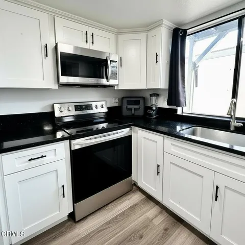 a kitchen with stainless steel appliances granite countertop white cabinets granite counter tops and a window
