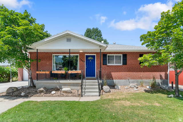 1489 North 400 West Bountiful, UT 84010 - Photo 3 of 47 Brick exterior with a covered porch featuring a vibrant blue front door, white trim, and dark window shutters