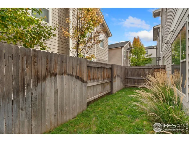 a view of backyard with wooden fence and large trees