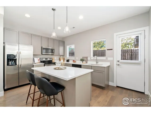 a open kitchen with stainless steel appliances granite countertop a sink dishwasher a stove a refrigerator with a dining table and chairs