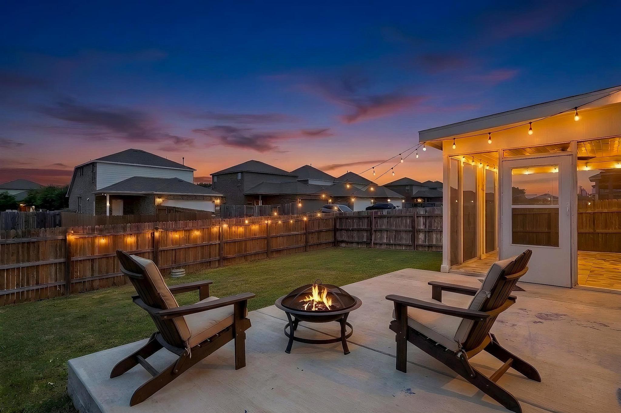 1341 Eagle Ray Street Leander, TX 78641 - Photo 26 of 37 Twilight glow illuminates this backyard patio, featuring a fire pit and string lighting for evening gatherings.