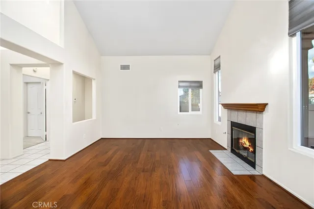 a view of an empty room with wooden floor fireplace and a window