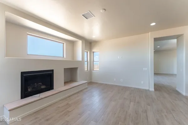 an empty room with wooden floor fireplace and windows