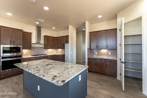 a kitchen with kitchen island granite countertop wooden cabinets and refrigerator