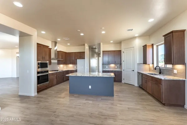 a kitchen with stainless steel appliances kitchen island granite countertop a refrigerator and a stove top oven