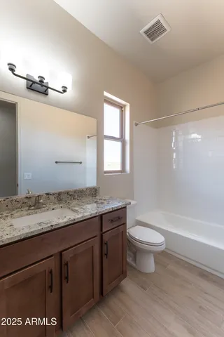 a bathroom with a granite countertop sink a toilet a mirror and bathtub