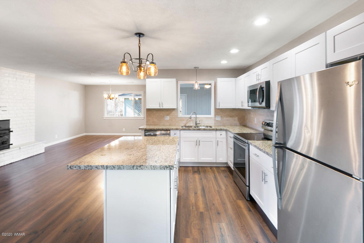 205 North 4th W Street Snowflake, AZ 85937 - Photo 9 of 24 a kitchen with granite countertop a refrigerator a sink dishwasher a stove top oven a counter space and wooden floor