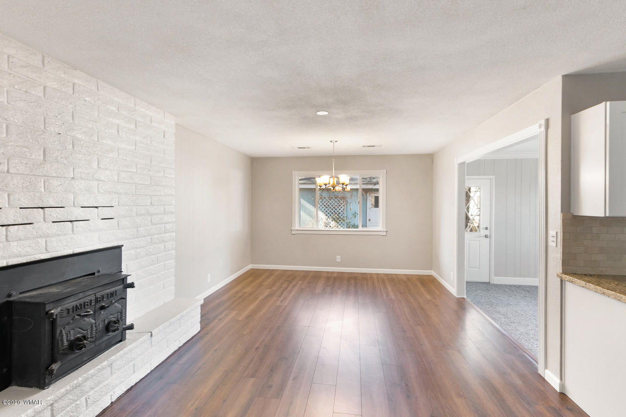 205 North 4th W Street Snowflake, AZ 85937 - Photo 10 of 24 an empty room with wooden floor a fireplace and windows