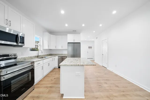 a kitchen with granite countertop stainless steel appliances and white cabinets