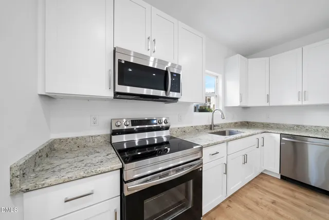 a kitchen with stainless steel appliances granite countertop white cabinets granite counter tops and a wooden floors