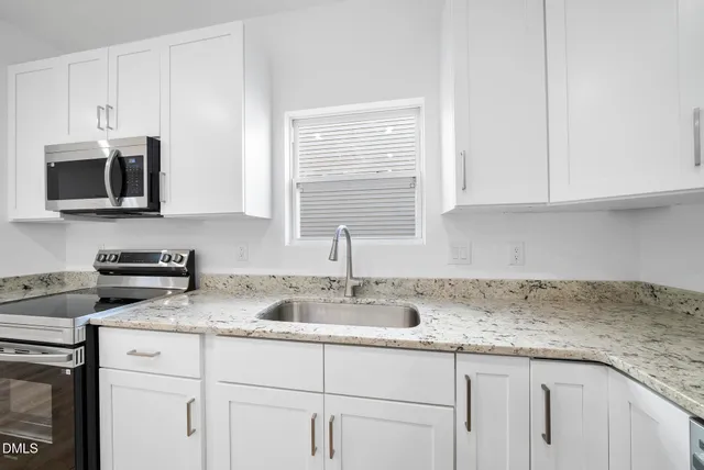 a kitchen with granite countertop white cabinets and a sink