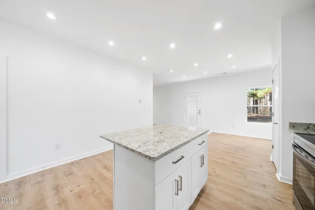 an empty room with kitchen appliances and wooden floor