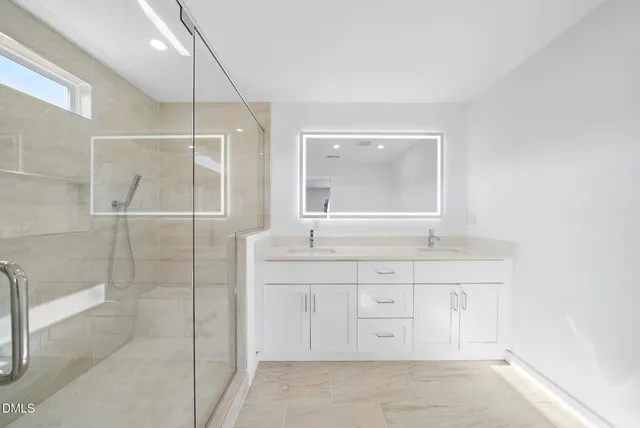 a bathroom with a granite countertop sink a mirror and a shower