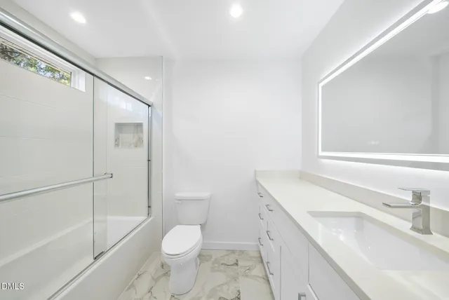 a bathroom with a granite countertop sink toilet and shower