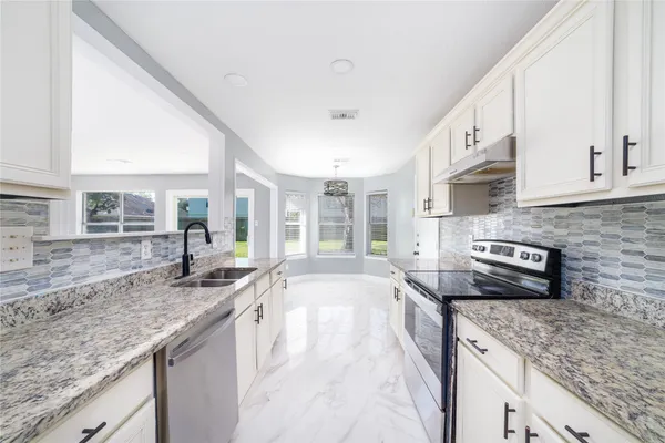 a large kitchen with granite countertop a sink a stove and cabinets