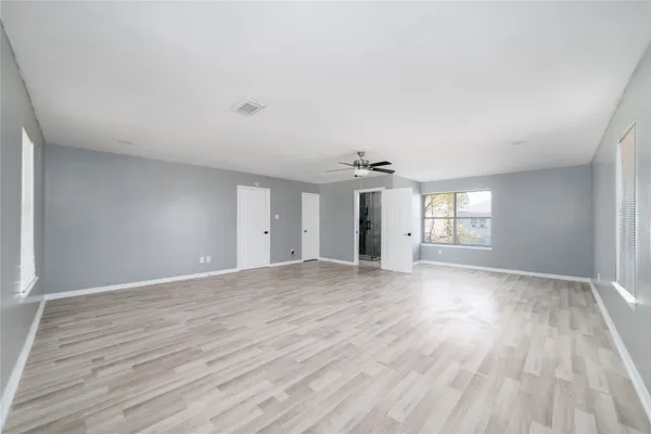 an empty room with wooden floor and windows